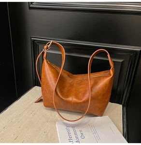 Detail of vintage brown PU leather bag showing vertical stitching and soft pleats