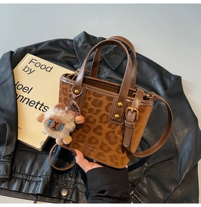 Detail of leopard print bucket bag with leather handles and sheep pendant on a jacket