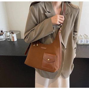 Close-up of brown oversized shoulder bag featuring metal logo and vintage flap pocket