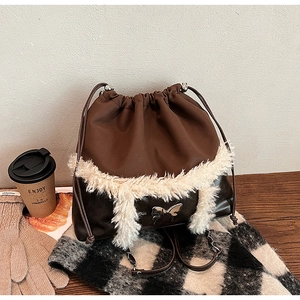 Detail view of winter bucket bag with faux fur trim, butterfly buckle, and autumn props
