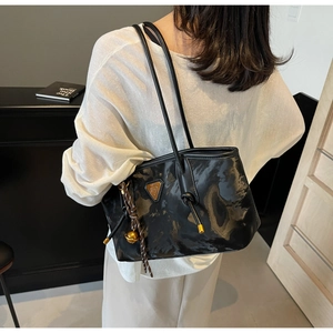 Détail du sac à main noir brillant avec texture moirée et logo triangulaire