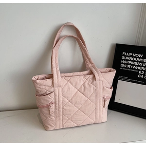 Detail of pink quilted tote bag with diamond stitching and side zipper pocket