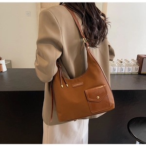 Detail of brown leather Hobo bag featuring a front pocket with gold hardware buckle