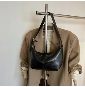 Detail of a black crescent hobo bag with sleek leather texture on a metal hanger