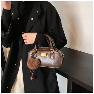 Detail view of brown vintage leather pillow bag with gold plate and plush charm