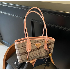 Détail du tissu à carreaux du sac cabas avec poignée en cuir rose et plaque dorée