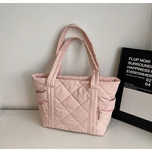 Close-up of pink quilted tote bag showing nylon texture and side zipper pockets