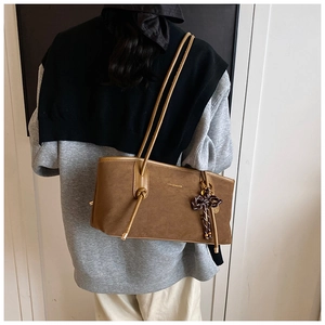 Detail of a brown matte suede tote bag with slim straps and side knot decoration