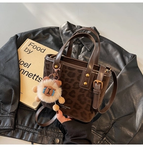 Detail of leopard print bucket bag with golden hardware and fuzzy blue-eye charm