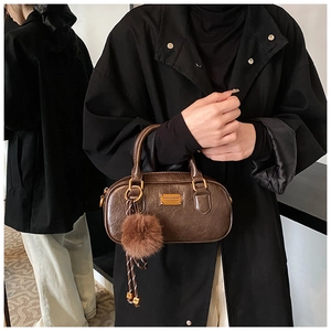 Mirror reflection showing dark brown Boston bag with gold zipper and pompom charm