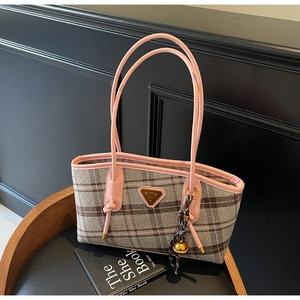 Détail du cabas à carreaux gris et rose avec logo en triangle et breloque cloche sur chaise
