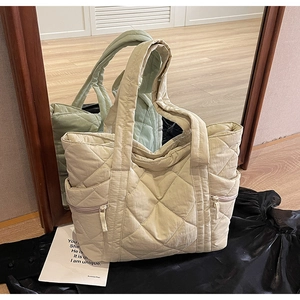 Detail of quilted tote bag with dual-side zip pockets and padded nylon finish