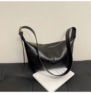 Detail of vintage black faux leather hobo bag with adjustable strap and gold zipper