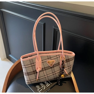 Détail des poignées roses et du tissu à carreaux gris avec logo sur un sac cabas