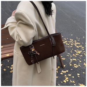 Detail of dark brown matte suede tote bag with golden logo and bow key chain ornament