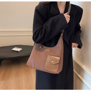Close-up of brown faux leather shoulder bag featuring gold hardware and logo plaque