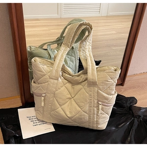 Detail of cream quilted tote bag showing rhombus stitching and side zipper pocket
