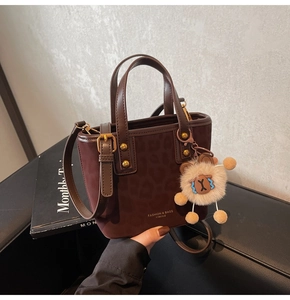 Detail of leopard print bucket bag with gold rivets and cute plush lion charm