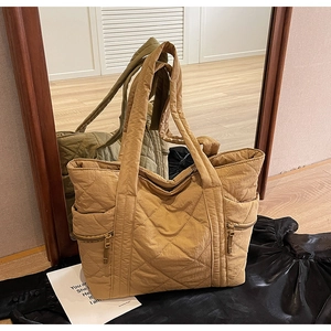 Detailed macro view of quilted khaki tote bag with dual gold zipper pockets and diamond pattern