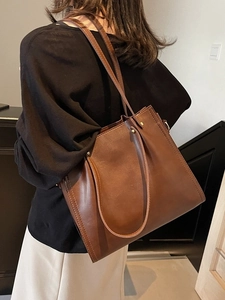 Minimalist dark brown leather tote bag with large capacity shown on model's shoulder