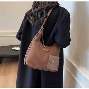 Detail of a brown leather hobo bag with a contrast magnetic pocket and metal logo