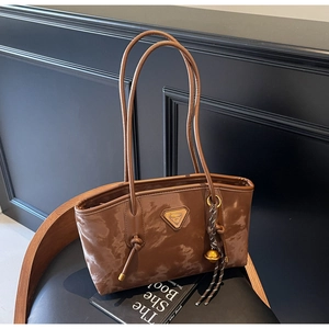 Détail d'un sac cabas marron caramel avec texture brillante et logo métallique chic