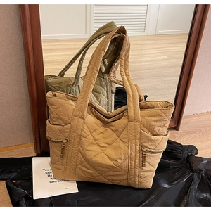 Detailed macro view of khaki quilted tote bag with diamond stitching and side zippers