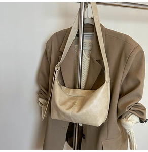 Detail shot of a creamy white crescent hobo bag with textured leather and zipper