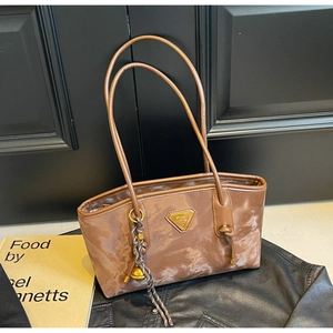 Détail d'un sac cabas marron à motif marbre avec logo triangle doré et fines bandoulières