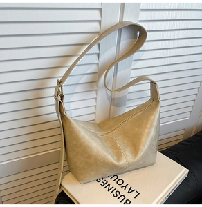 Detail of beige hobo bag with pleated leather texture and gold metallic buckle strap