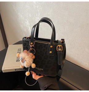 Detail of black leopard print bucket bag with gold hardware and plush bear charm