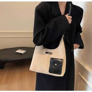 Detail of beige and black hobo bag with gold hardware and side pocket on a table