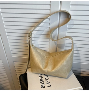 Close-up of beige moon bag showing pleated leather texture and metal zipper detail