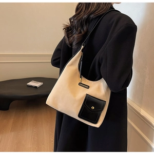 Detail of beige hobo bag with contrast black pocket and gold button on model