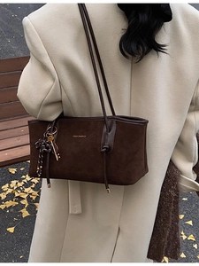 Brown suede tote bag with gold lettering shown in an autumn park setting with leaves