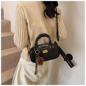Detail of black Boston bag featuring glossy PU texture and golden metal hardware