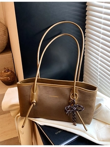 Brown matte tote bag with shoulder strap and stylish charm in natural sunlight
