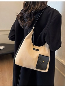 Large beige and black contrast hobo tote bag worn by a model in a black wool coat