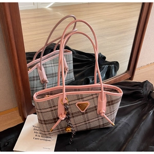 Gros plan d'un sac cabas à carreaux avec poignées en cuir rose et plaque logo en métal