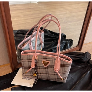 Détail du sac cabas en toile à carreaux avec bordure en cuir rose et plaque logo dorée