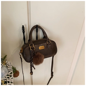 Detail of a brown vintage Boston bag with gold plaque and faux fur pompom charm
