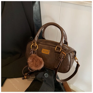 Detail of dark brown Boston bag with vintage textured leather and golden metal logo plate