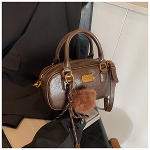 Detail of deep brown Boston bag with wrinkled texture and golden metal logo plate