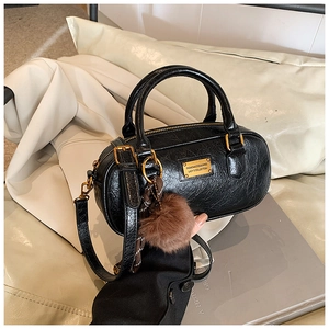 Detail of black wax leather Boston bag with gold plate and brown plush charm