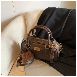 Detail of dark brown boston bag with crinkle texture leather and gold metal logo plate