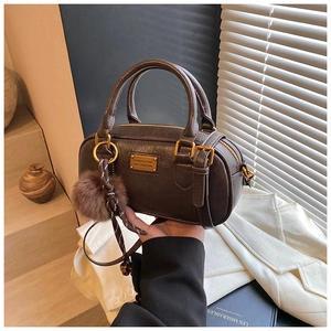 Detail of dark brown Boston bag with textured leather, gold plate and plush charm