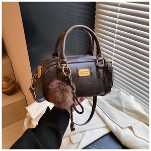Close-up of deep brown boston bag featuring vintage pleated texture and gold hardware detail