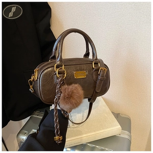 Close-up of vintage brown leather Boston bag with soft pleats and golden plaque