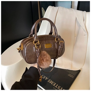 Detail of dark brown Boston bag with oil-leather texture, silk scarf and fur pompom
