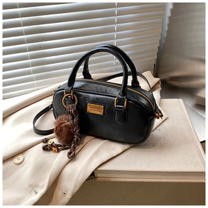 Detail of black pleated texture Boston bag with gold zipper and plush ball charm